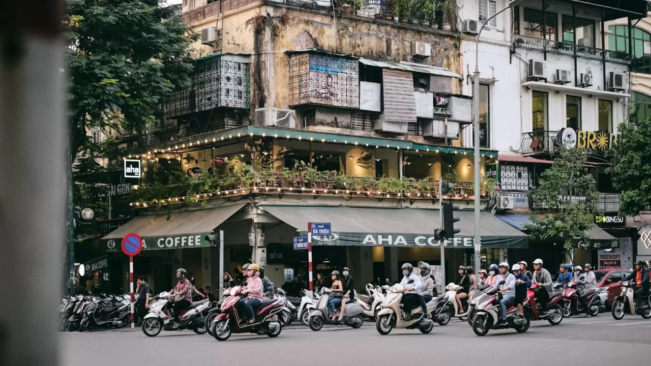 Dòng xe máy qua ngã tư phố cổ Hà Nội với quán cà phê và nhà cũ