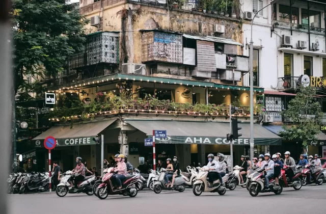 Dòng xe máy qua ngã tư phố cổ Hà Nội với quán cà phê và nhà cũ