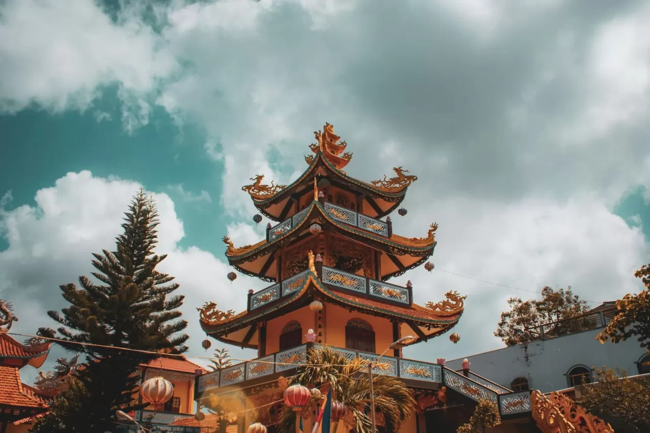 Ngôi chùa nhiều tầng mái cong đỏ nâu dưới nền trời xanh mây trắng ở Huế