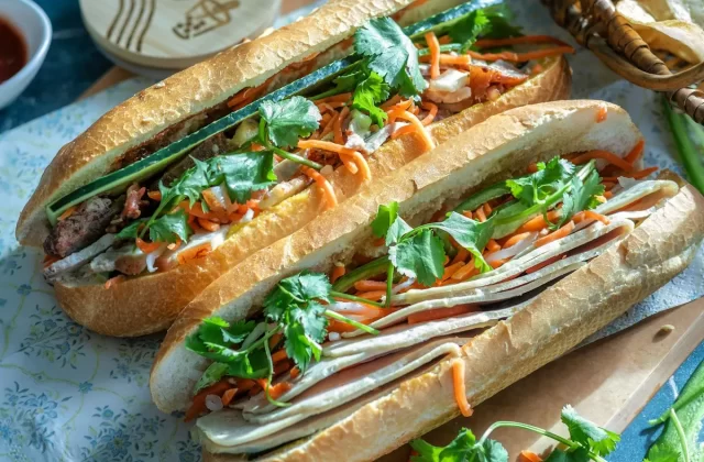 Những ổ bánh mì kẹp thịt, rau và đồ chua bên chén sốt