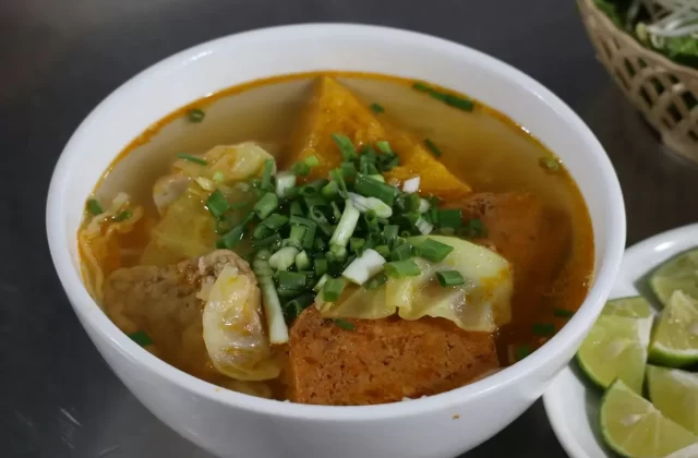 Tô bún nước dùng đỏ cam với đậu phụ, chả và rau thơm (ảnh gần giống bún bò)