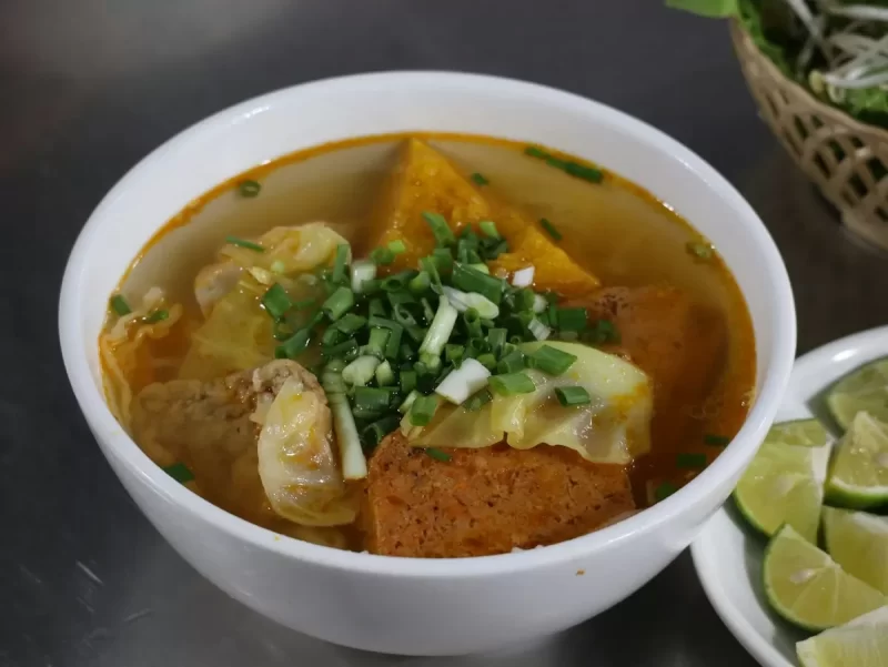Tô bún nước dùng đỏ cam với đậu phụ, chả và rau thơm (ảnh gần giống bún bò)