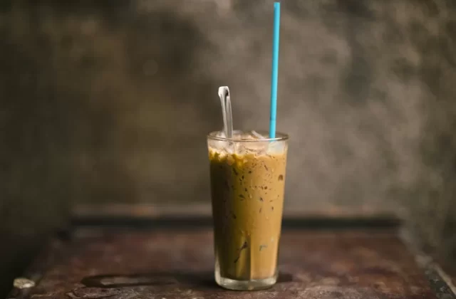 Ly cà phê sữa đá cao với ống hút xanh