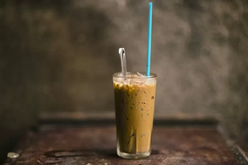 Ly cà phê sữa đá cao với ống hút xanh