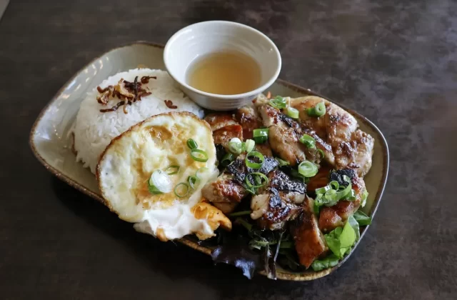 Đĩa cơm tấm với thịt nướng, trứng ốp la và chén nước mắm