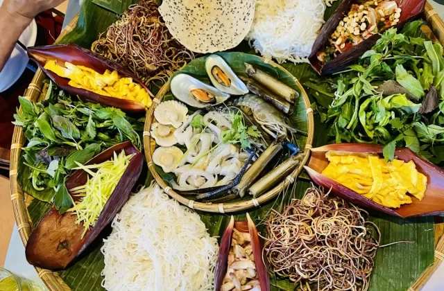 Mâm lá chuối bày món ăn vùng cao với bánh tráng, rau và hoa chuối
