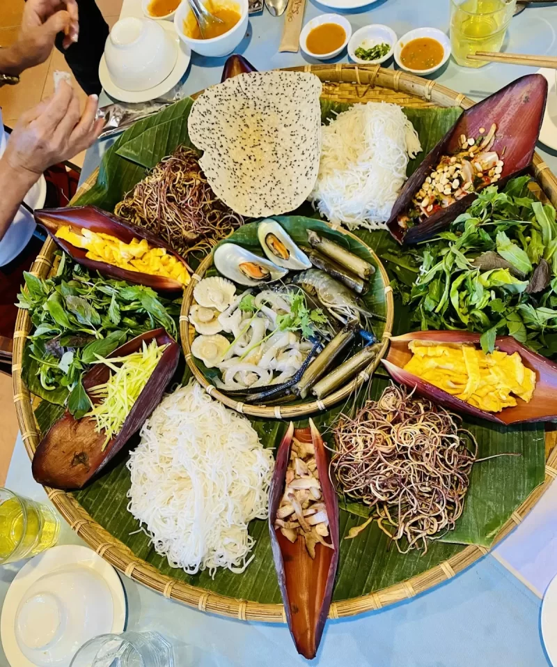 Mâm lá chuối bày món ăn vùng cao với bánh tráng, rau và hoa chuối