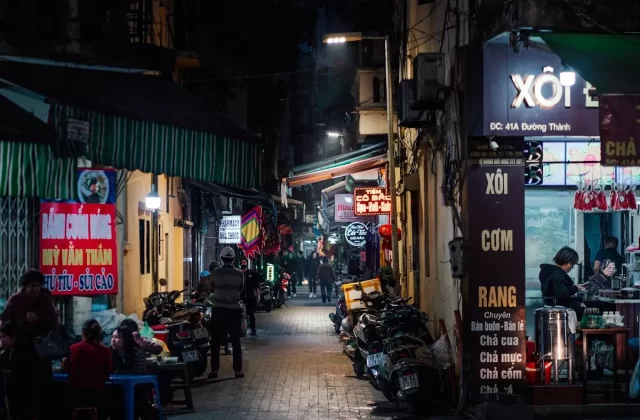 Con phố cổ Hà Nội về đêm với quán ăn và bảng hiệu đèn