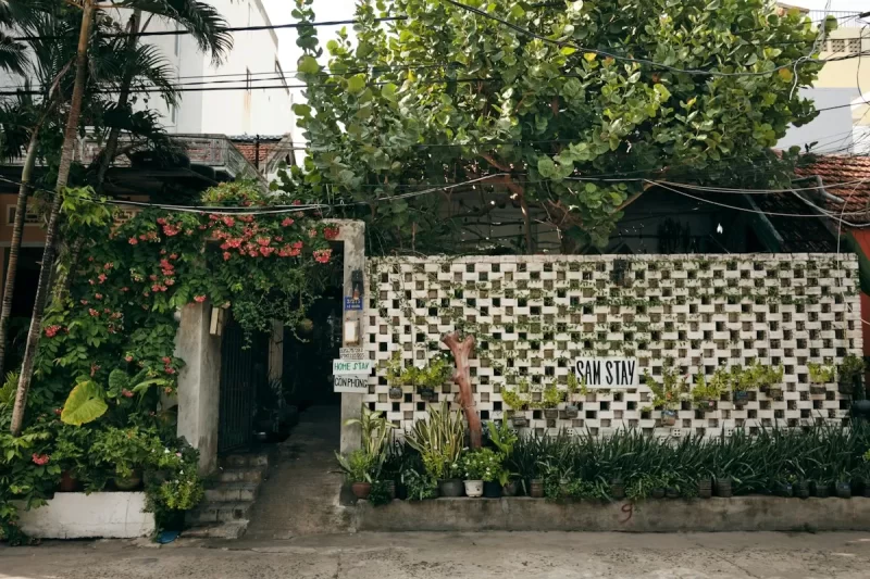 Lối vào homestay với tường gạch thông gió trắng và cây xanh
