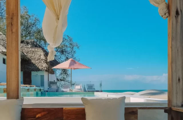 Phòng nghỉ mở ra hồ bơi và biển xanh với rèm trắng bay