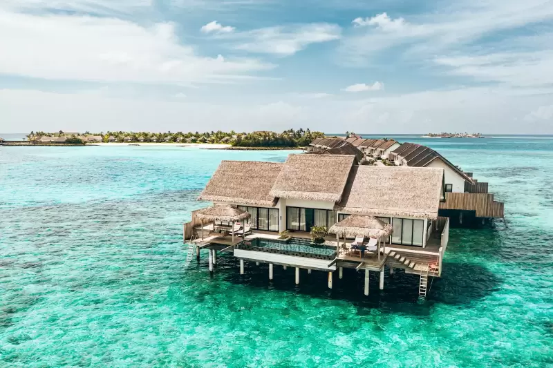 Biệt thự gỗ trên mặt nước trong vắt dưới bầu trời xanh ở một đảo resort Maldives