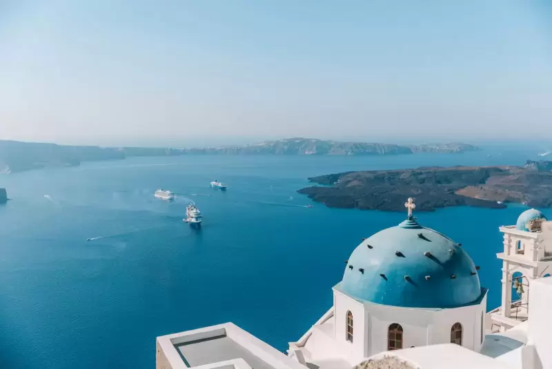 Nhà thờ mái vòm xanh nhìn ra biển Aegean từ sườn caldera Santorini