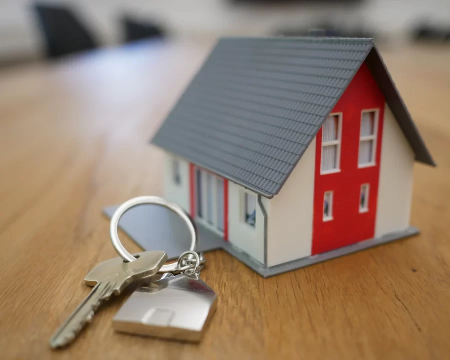 Chìa khóa nhà đặt cạnh mô hình ngôi nhà trên bàn gỗ
