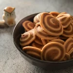 Bánh quy cuộn xoắn hai màu nâu vàng xếp đầy trong chảo gang đen