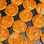Những chiếc bánh pía vỏ vàng óng rắc mè xếp sát nhau trên khay nướng