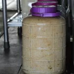 Hũ nhựa lớn đựng mắm ủ màu hồng nhạt, nắp tím buộc chặt