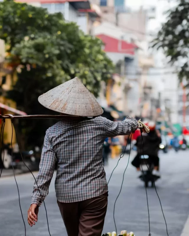 Người bán hàng rong đội nón lá gánh quang gánh trên phố Hà Nội