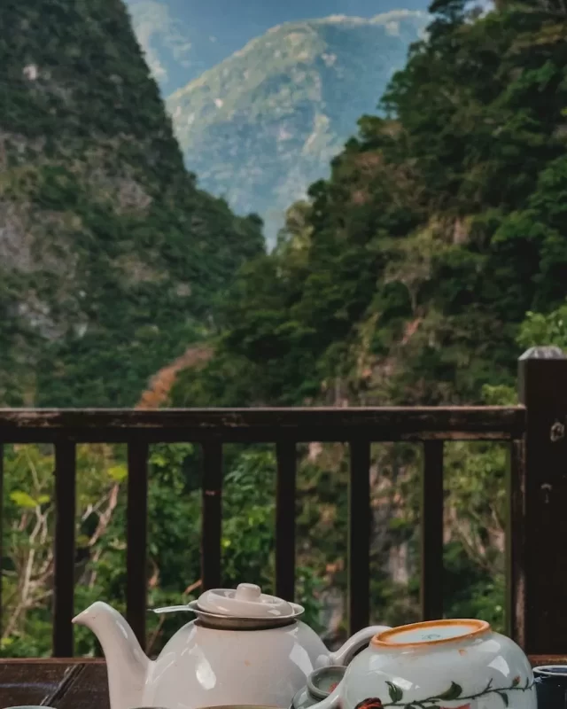 Ấm trà trên ban công gỗ nhìn ra núi đá xanh thẫm và thung lũng