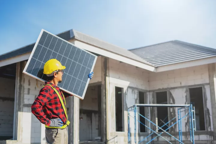 Kỹ thuật viên cầm tấm pin trước ngôi nhà