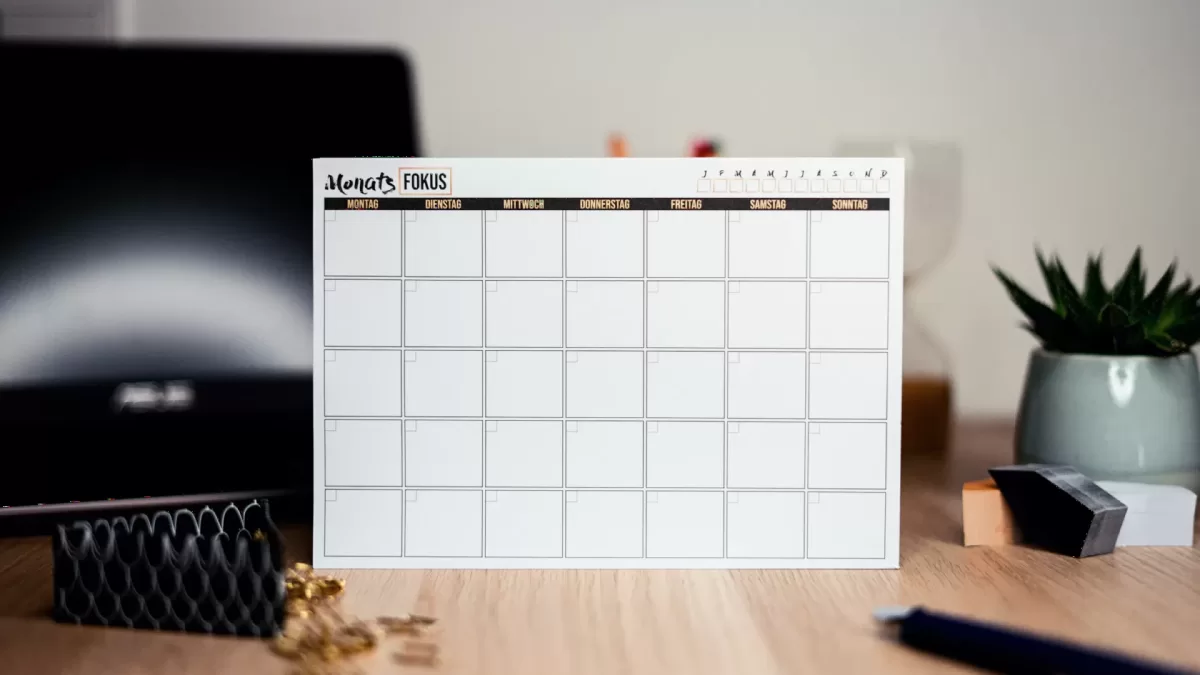Tấm lịch tháng trên bàn làm việc cạnh cây xanh nhỏ