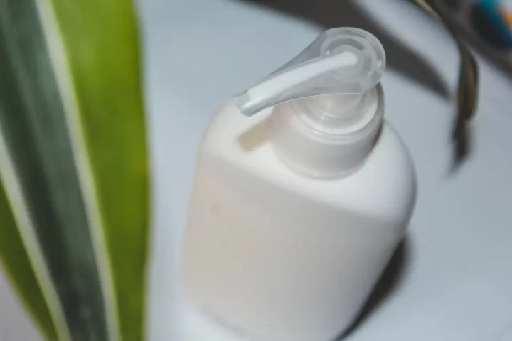 Chai sữa tắm vòi nhấn màu trắng cạnh lá xanh
