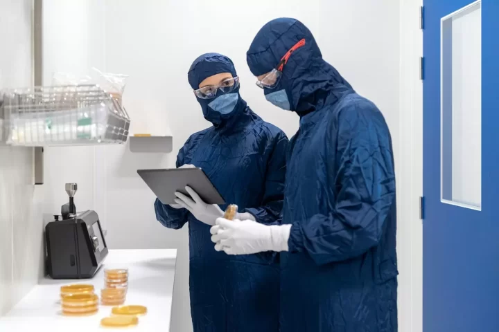 Hai nhân viên mặc đồ phòng sạch đeo khẩu trang trao đổi kết quả kiểm tra