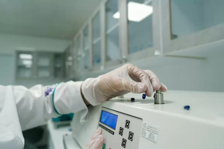 Nhân viên phòng thí nghiệm đeo găng tay vận hành máy phân tích