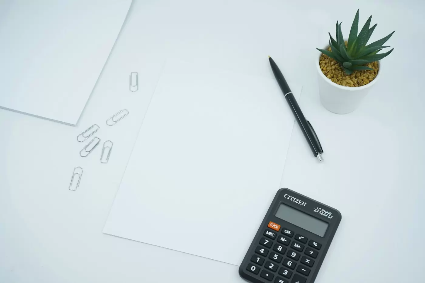 Máy tính bỏ túi và bút đặt trên tờ giấy trắng