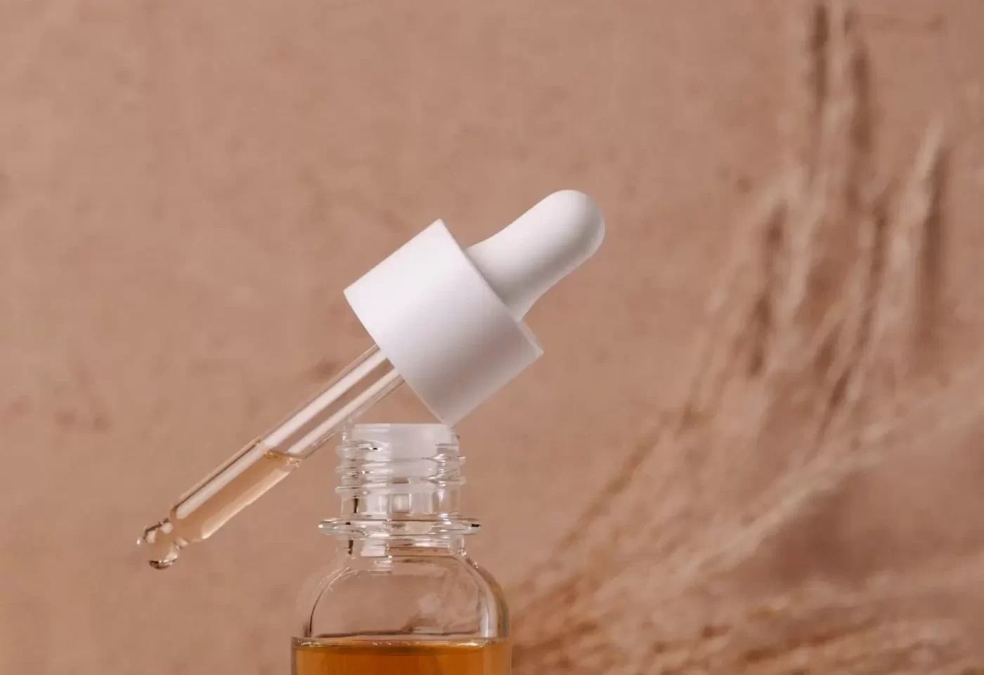 Chai serum nhỏ giọt bên cành cỏ khô