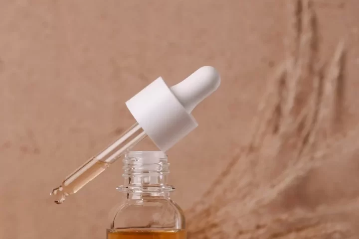 Chai serum nhỏ giọt bên cành cỏ khô