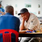 Hai người bạn ngồi chơi bài ở bàn chung, không khí sôi động tại homestay Hẻm Nướng Đà Lạt