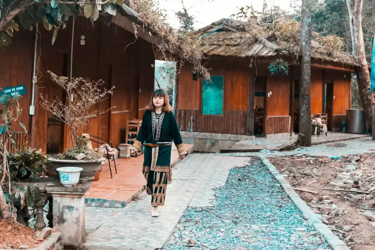 Người phụ nữ đi bộ gần ngôi nhà nâu giữa bản làng cao nguyên đá Hà Giang
