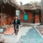 Người phụ nữ đi bộ gần ngôi nhà nâu giữa bản làng cao nguyên đá Hà Giang