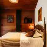 Phòng ngủ ốp gỗ ấm với đầu giường chạm khắc và đèn vàng dịu tại Nhà Trình Tường Hà Giang