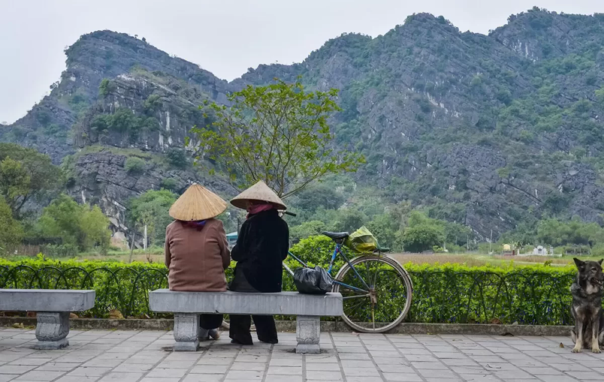 Hai du khách ngồi nghỉ bên cánh đồng và núi đá