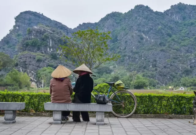 Hai du khách ngồi nghỉ bên cánh đồng và núi đá