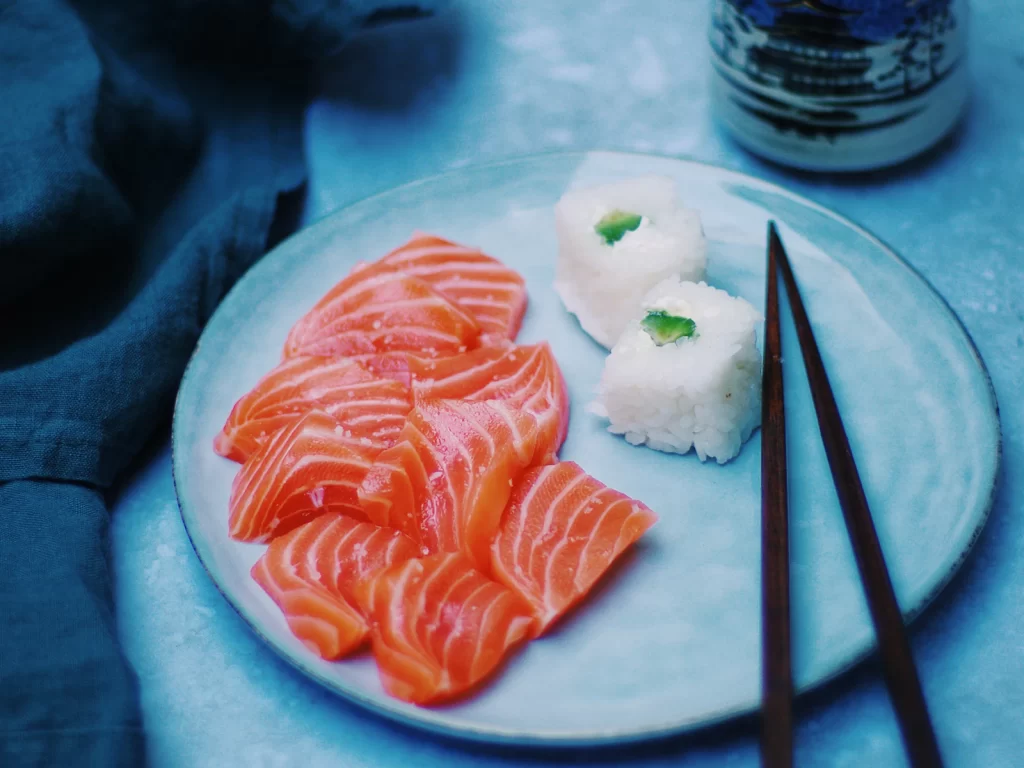 Đĩa sashimi cá hồi và sushi bày cùng đũa