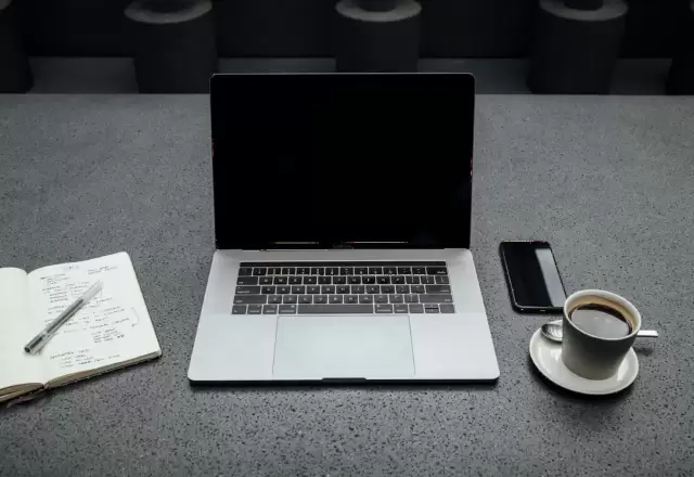 Bàn học với laptop, cốc cà phê, điện thoại, sổ tay và bút