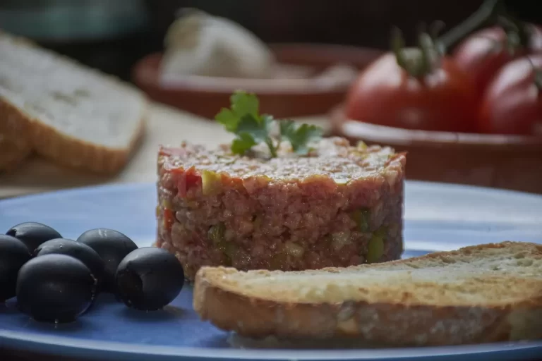 Tartare bò cắt khối gọn gàng với bánh mì và ô liu