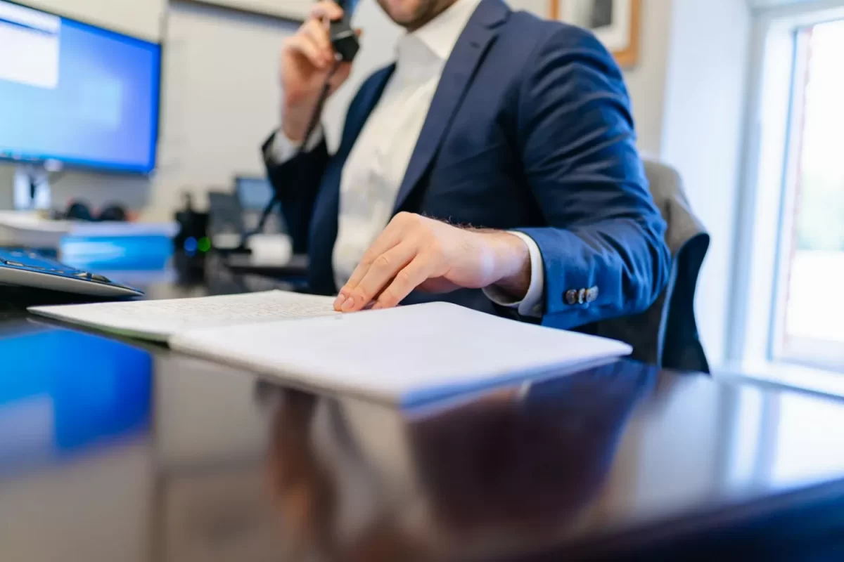 Người đàn ông mặc vest nghe điện thoại bên tờ giấy tài liệu