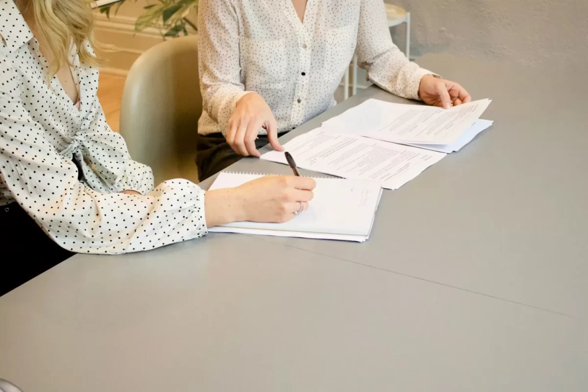 Hai người ngồi bàn ký giấy tờ hợp đồng trước mặt luật sư