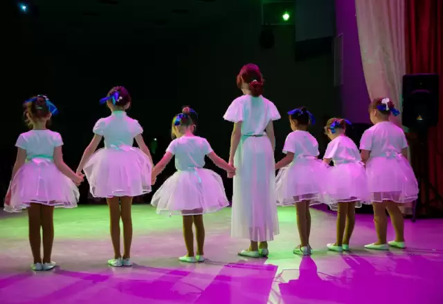 Nhóm bé gái mặc váy tutu hồng tay trong tay biểu diễn trên sân khấu