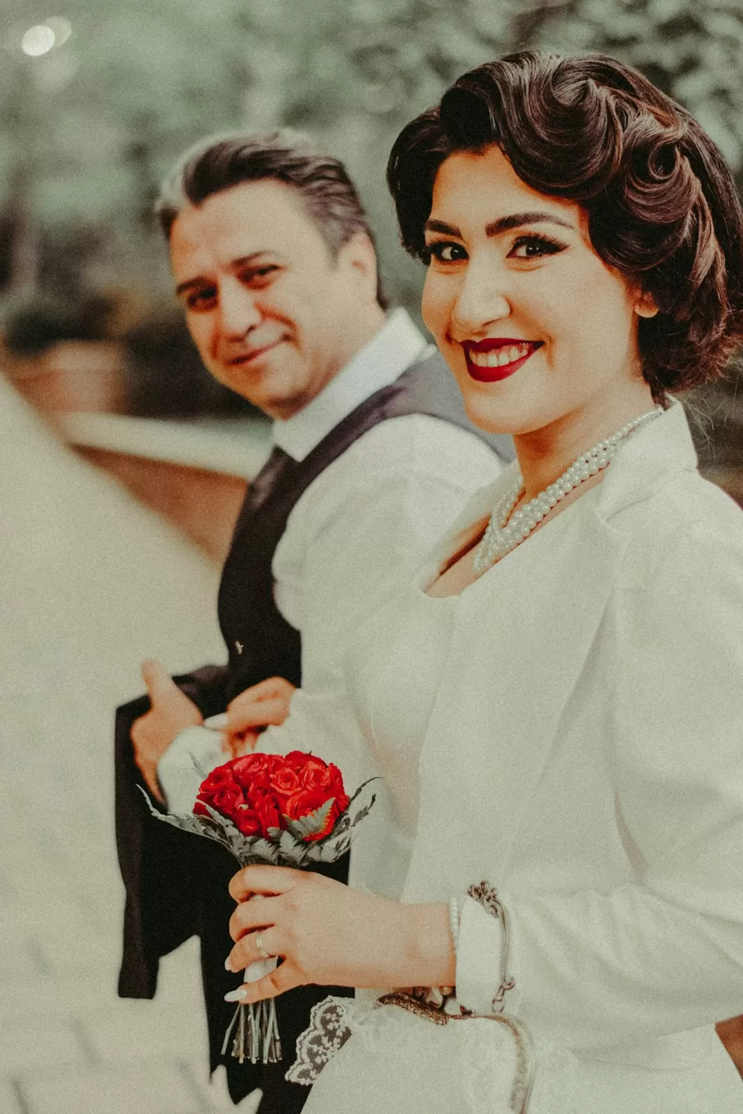 Cặp đôi phong cách vintage cười rạng rỡ, cô dâu cầm bó hồng đỏ