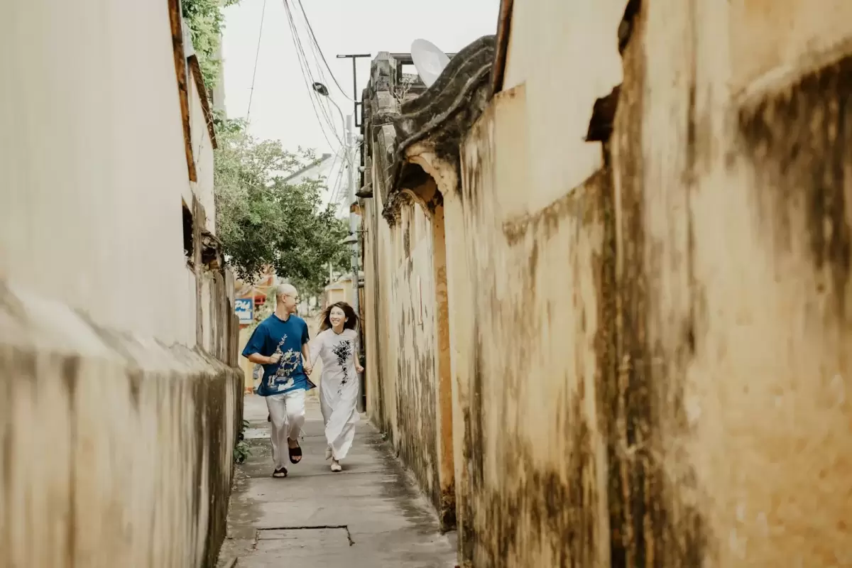 Ảnh cưới Hội An phong cách Cổ điển: người đi trong con hẻm cũ có tường vàng