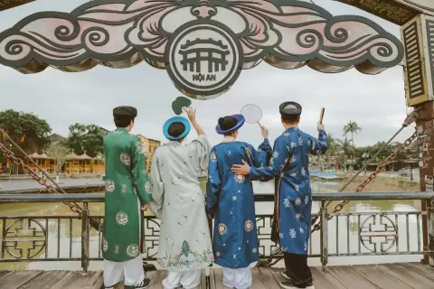 Ảnh cưới Hội An phong cách Cổ điển: nhóm bốn người mặc áo dài đứng quay lưng trên cây cầu cổ
