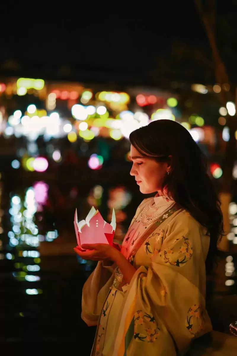 Ảnh cưới Hội An phong cách Cổ điển: cô gái áo dài vàng cầm đèn hoa đăng bên dòng sông ban đêm