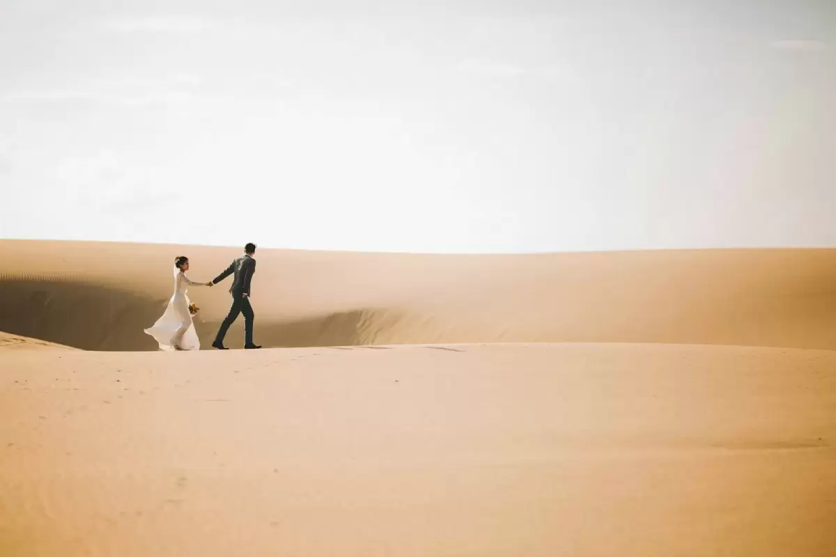 Ảnh cưới Mũi Né phong cách Ngoại cảnh: chú rể đứng một mình trên đồi cát rộng dưới bầu trời nhạt