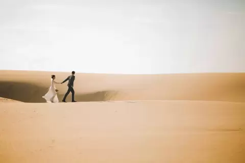 Ảnh cưới Mũi Né phong cách Ngoại cảnh: chú rể đứng một mình trên đồi cát rộng dưới bầu trời nhạt
