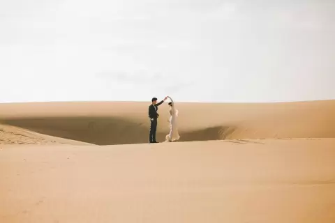 Ảnh cưới Mũi Né phong cách Ngoại cảnh: hai người nhỏ đứng giữa đồi cát lúc nắng dịu