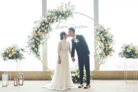 Ảnh cưới Sài Gòn phong cách Hàn Quốc: cô dâu chú rể hôn nhau dưới vòm hoa trắng cạnh cửa sổ lớn